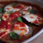 Melanzane alla parmigiana appena sfornate, con strati di formaggio fuso e salsa di pomodoro.